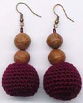 Fall fashion accessory wear distributor supplying threader earrings with wooden beads above maroon woolen ball